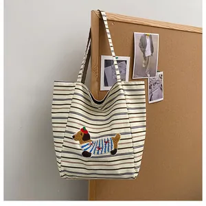 Detail of corduroy tote bag featuring a cute dachshund puppy embroidery on beige fabric