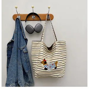 Detail of canvas tote bag featuring embroidered dachshund dog and striped pattern
