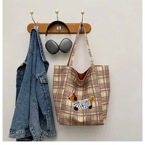 Detail of plaid canvas tote with a cute puppy patch embroidery hanging on a wooden hook