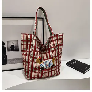 Close-up of red and green plaid canvas tote bag with cartoon dachshund embroidery details