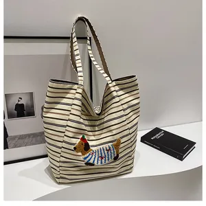 Close-up of canvas tote bag featuring striped pattern and dachshund plush embroidery