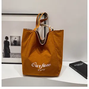 Detail of yellow canvas tote bag with checkered lining and Ourfave Party logo
