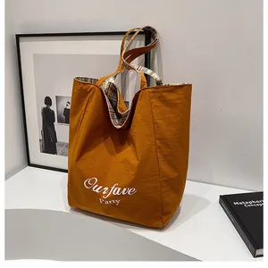 Detail of orange canvas tote bag with Ourfave Party print and blue checkered lining