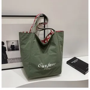 Detail of army green canvas tote bag featuring red-white plaid lining and graphic text