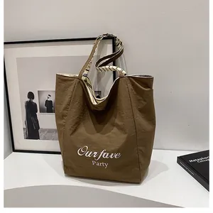 Detail of a large brown canvas tote bag with white art text and striped handle straps