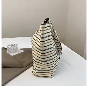 Side view of a large capacity striped canvas tote bag with textured corduroy fabric detail