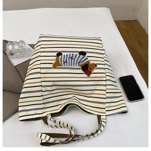 Detail of canvas tote bag featuring cute dog embroidery and stylish striped pattern