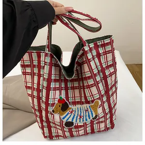 Detail of red and green plaid canvas tote bag featuring a cute dachshund embroidery patch