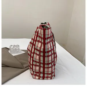 Detail of a large red and green plaid canvas tote bag in a cozy home lifestyle setting