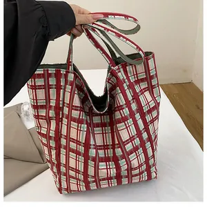 Detail of red and green checkered canvas tote bag with reinforced handles in lifestyle setting