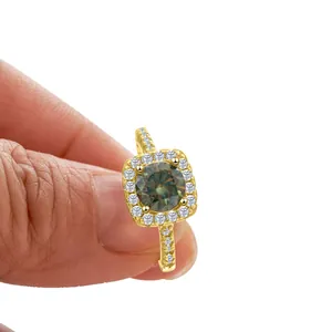 S925 silver 1ct moissanite halo ring in gold finish held by hand on white background