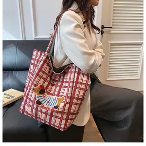 Detail of red checkered canvas tote bag with dachshund embroidery on a white blazer model