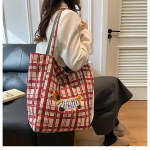 Detail of red checkered canvas tote bag with embroidered dog patch and dual-style straps