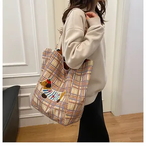 Close-up of a large checkered canvas tote bag featuring a cute dachshund embroidery patch