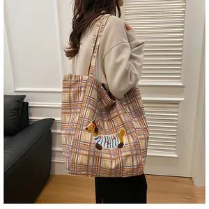 Detailed view of large checkered tote bag with cute puppy embroidery on a model shoulder