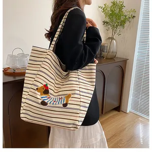 Close-up of canvas tote bag featuring striped pattern and cute dachshund embroidery detail