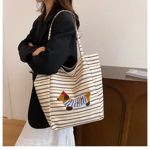 Close-up of striped canvas tote bag with 3D plush puppy embroidery and dual shoulder straps