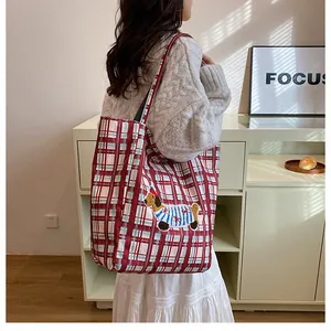 Close-up of red and white checkered tote bag with dachshund embroidery on model shoulder