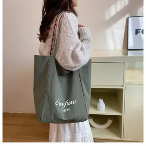 Detail of green canvas tote bag with white lettering and comfortable shoulder straps