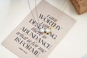 Classic 2ct moissanite bezel pendants in silver and gold on a soft matte display card