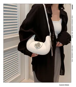 Detail of white half-moon underarm bag with decorative silver metal flower buckle