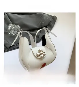 Detailed view of silver flower buckle on cream white faux leather underarm handbag