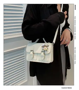Chic cream vintage crossbody bag styled with a decorative cartoon doll and slim shoulder strap