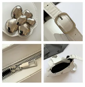 Close-up of white leather underarm bag with silver flower buckle and metal zipper details