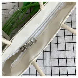 Vista dettagliata della borsa in nylon bianco sporco con cerniera argento e manico fisso