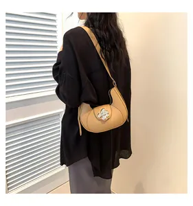 Detailed view of beige hobo bag featuring a silver floral clasp and half-moon leather design