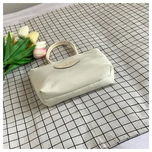 Dettaglio di una borsa beige in nylon con logo a cuore su sfondo a quadretti e tulipani
