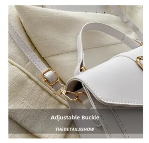Detail shot of the golden adjustable metal buckle and hook on a white PU leather bag
