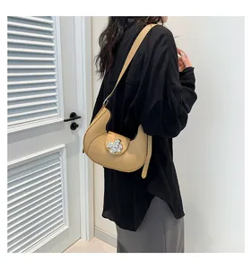Detailed view of khaki crescent shoulder bag with silver flower buckle and strap