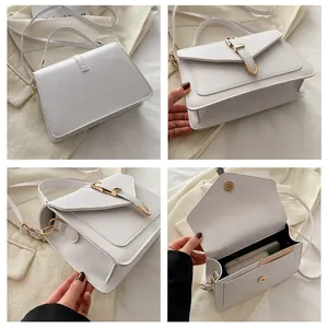 Detail view of white square handbag with gold hardware lock and interior phone storage