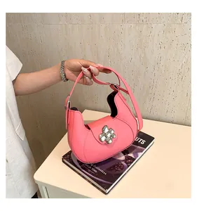 Pink crescent saddle bag featuring a large silver flower buckle and two straps