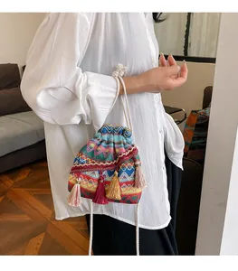 Dettaglio della borsa a secchiello boho intrecciata con motivi geometrici vivaci e nappe
