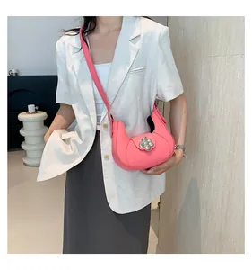 Detail of pink half-moon underarm bag featuring a silver floral metal buckle accent