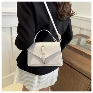 Detail showing an ivory white crossbody bag with V-shaped flap and gold metal buckle