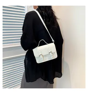 Detailed side view of a white vintage crossbody square bag with gold metal buckle straps