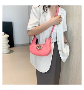 Detailed side view of pink crescent shoulder bag with floral buckle on a model