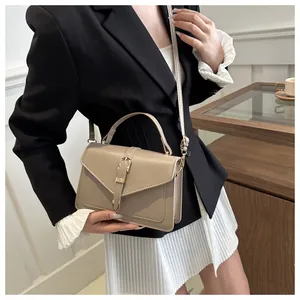 Khaki PU leather crossbody bag featuring top handle and gold hardware on model