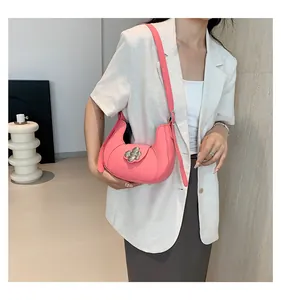 Detail of pink half-moon underarm bag with silver floral accent on beige blazer