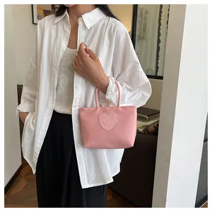 Dettaglio ravvicinato di una borsa in nylon rosa con toppa a cuore e smiley