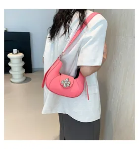 Side view of a pink crescent-shaped shoulder bag with a silver floral metal buckle