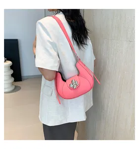 Detail view of pink crescent shoulder bag with silver flower buckle worn by a model