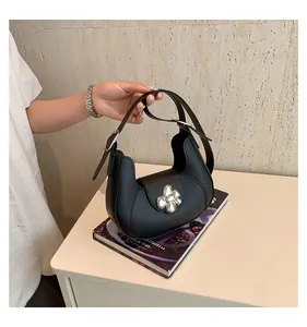 Detail of a black crescent shoulder bag featuring a decorative silver floral metal buckle