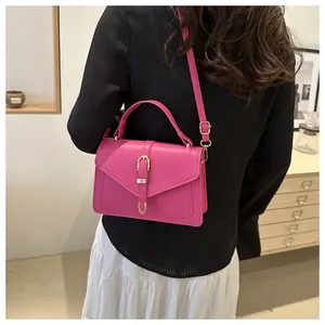 Détail d'un sac bandoulière en cuir magenta avec boucle dorée sur un fond minimaliste