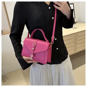 Close-up of bright pink leather crossbody bag with gold buckle on white skirt model