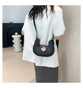 Detail of black leather crescent underarm bag featuring a crystal flower clasp