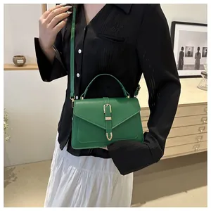Detail of green PU leather crossbody bag with gold buckle and adjustable shoulder strap